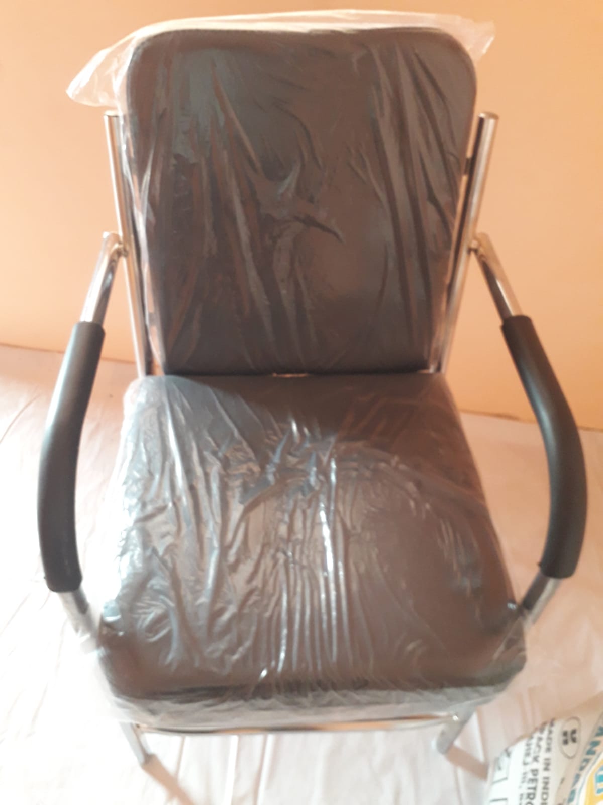 Black cushioned office visitor chair with metal frame and armrests